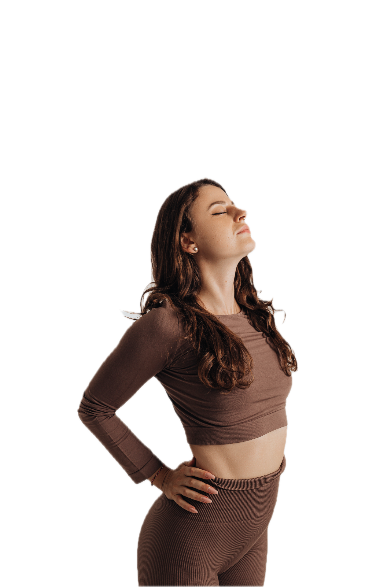 Randa Romanova standing tall with eyes closed in a fitted brown practice set